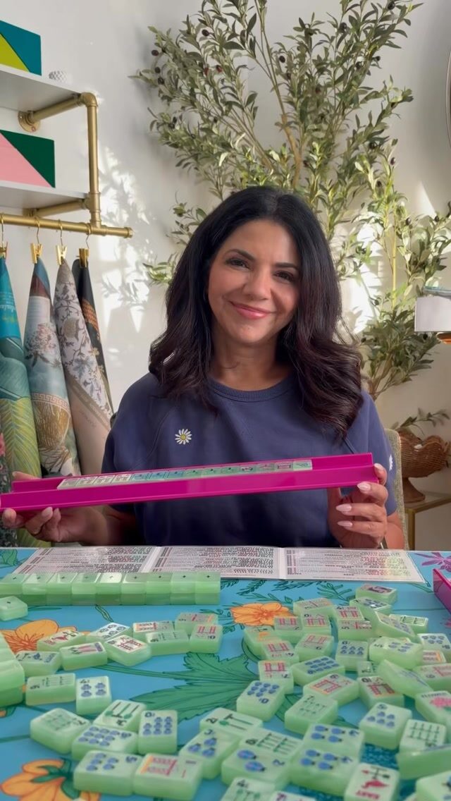 Moni holding up a rack of tiles over a table set for a lesson.